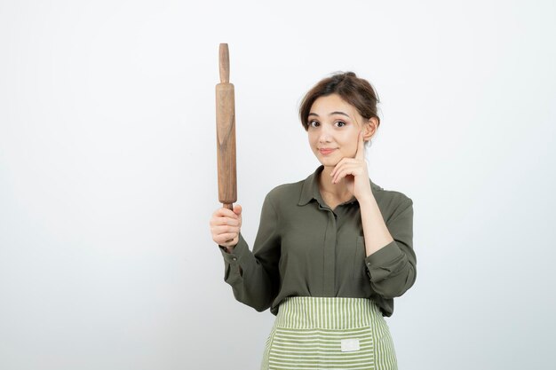 麺棒を持っているエプロンのきれいな女性の肖像画。高品質の写真