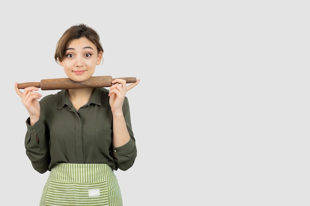 Portrait of pretty woman in apron holding a rolling pin