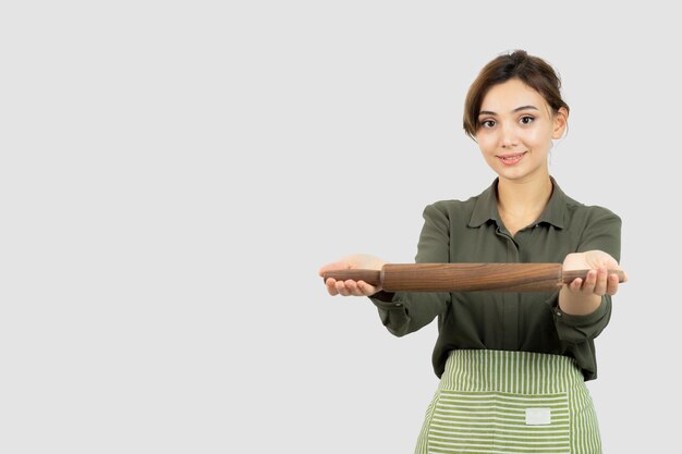 Portrait of pretty woman in apron showing a rolling pin