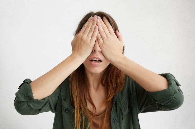 Foto gratuita ritratto di donna graziosa che copre gli occhi con le mani. giovane donna disperata che nasconde il suo viso non volendo vedere nessuno.