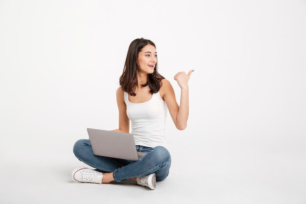 Portrait of a pretty woman dressed in tank-top holding laptop