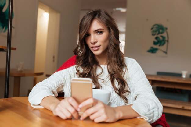 Ritratto di una donna graziosa che tiene telefono cellulare