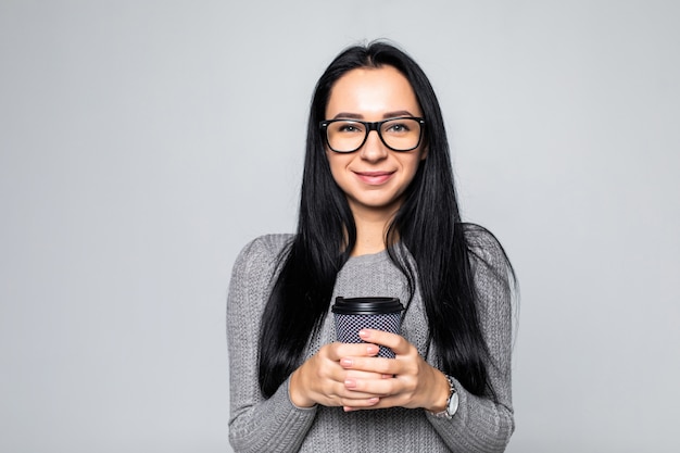 Portrait of a pretty woman holding takeaway coffee cup isolated over gray wall