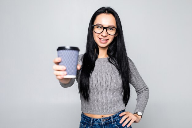Portrait of a pretty woman holding takeaway coffee cup isolated over gray wall