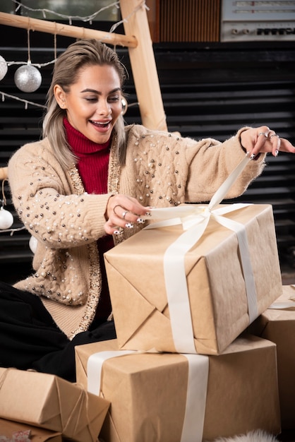 Портрет красивой женщины, открывающей коробку рождественского подарка