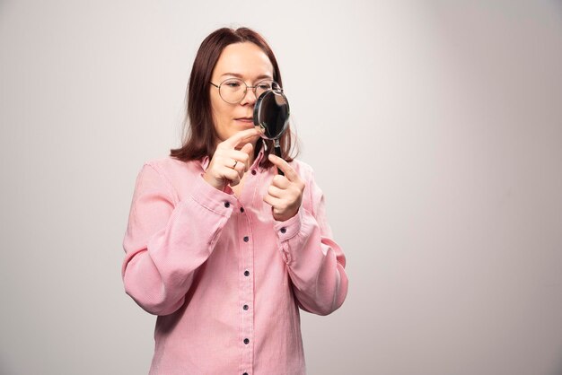 Portrait of pretty woman in pink clothesholding a magnifying glass. High quality photo