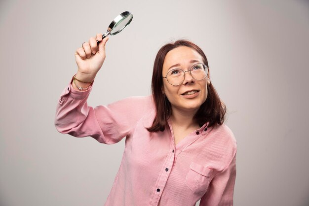 Portrait of pretty woman in pink clothesholding a magnifying glass. High quality photo