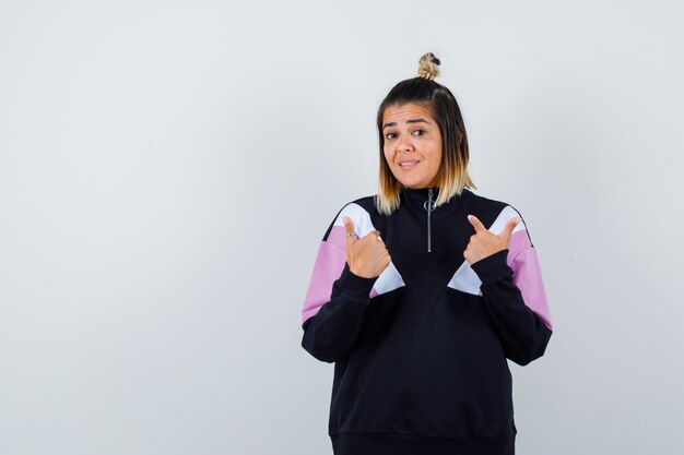 Portrait of pretty woman pointing at herself in sweatshirt and looking surprised