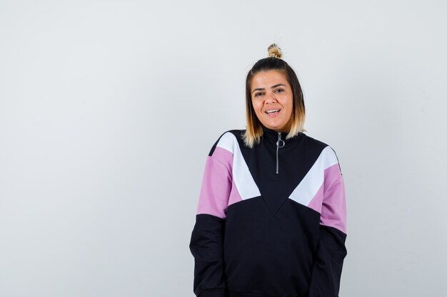 Portrait of pretty woman posing while standing in sweatshirt and looking pleased