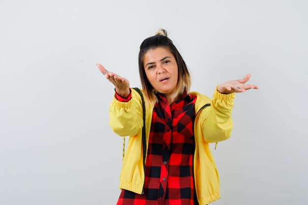 Portrait of pretty woman stretching hands, giving hug at camera in shirt, jacket and looking careful front view