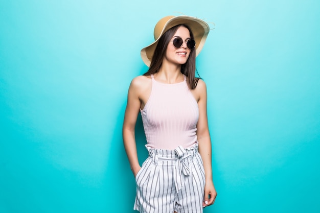 Portrait of pretty woman in sunglasses and hat over blue colorful wall. Summer vocation.