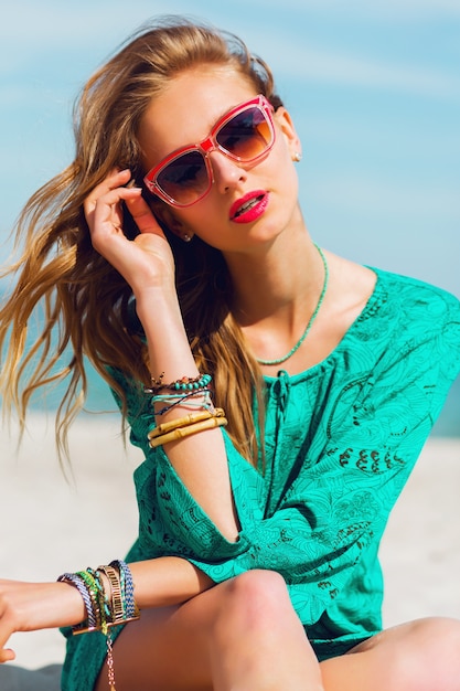 Portrait of pretty young blonde beautiful woman in cool sunglasses posing on the sunny tropical beach