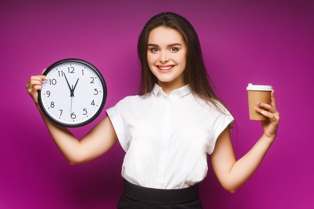 Portrait of a pretty young brunette businesswoman standing isolated on violet, holding cup of coffee.