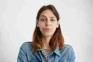 Free photo portrait of pretty young female raising her eyebrow with wonder dressed in denim jacket isolated. suspicious woman frowning her face.