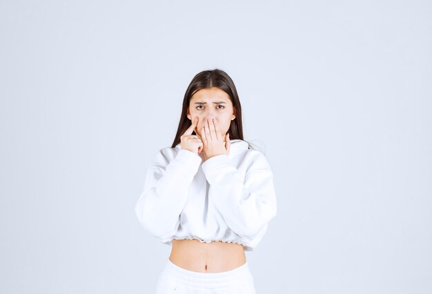 Portrait of a pretty young girl model covering mouth with a hand.