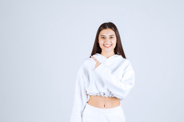 Portrait of a pretty young girl model pointing away with index fingers.