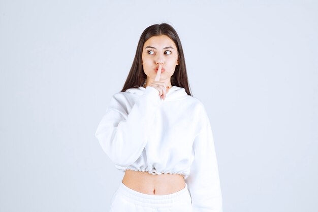 Portrait of pretty young girl model showing silent sign.