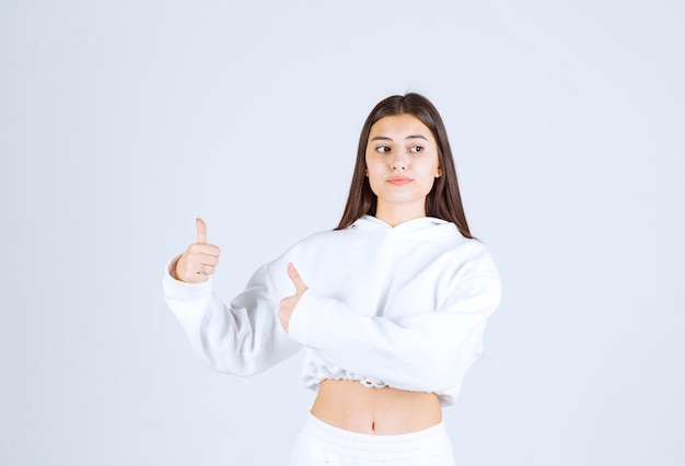 Portrait of pretty young girl model showing thumbs up.