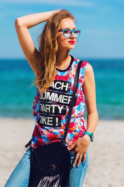 Portrait of pretty young sensual stunning woman with blond hairs and sunglasses posing on the paradise tropical beach