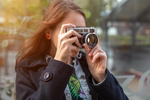 ヴィンテージのレトロなカメラで写真を撮るかなり若い観光客の肖像画。ストリートスタイル。ライフスタイル