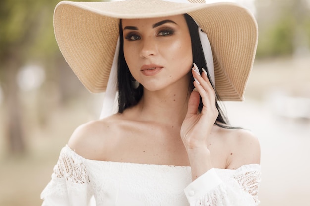 Portrait of a pretty young woman in hat and dress outdoor