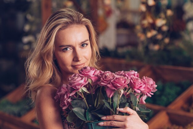 Portrait of pretty young woman holding pink rose bouquet