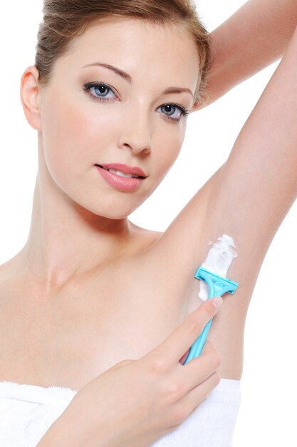 Portrait of pretty young woman shaving underarm with razor