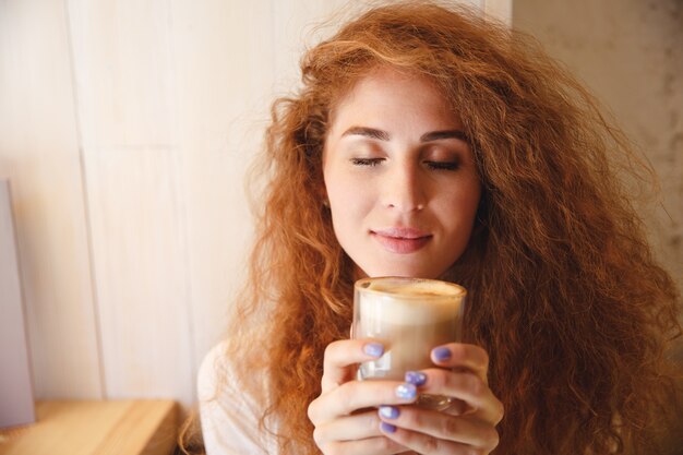 Portrait of a pretty young woman smelling her coffee drink