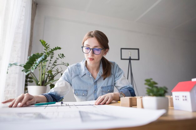 Portrait of pretty young woman working on blueprint at working place