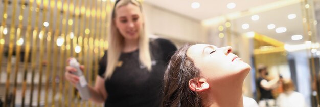 Portrait of professional beauty salon worker fixing wavy hairstyle with hair spray brunette