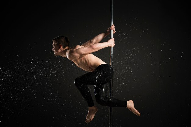 Portrait of professional male model performing a pole dance