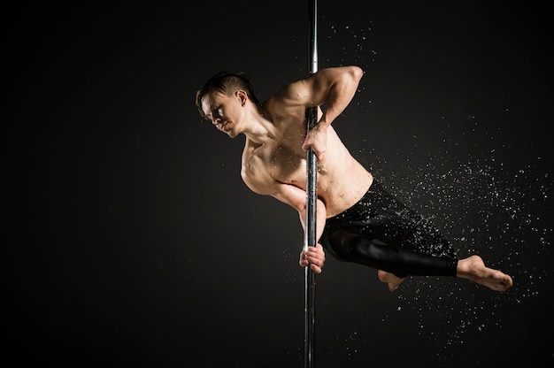 Portrait of professional male model performing a pole dance