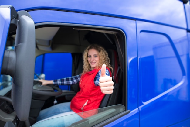 Portrait of professional truck driver showing thumbs up and smiling