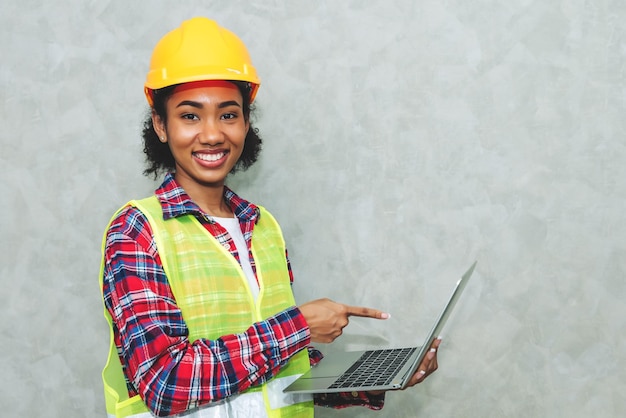 Free photo portrait of professional young black woman civil engineer architecture worker wearing hard hat safety for working in construction site or warehouseusing laptop for work