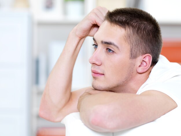 Portrait  profile of thoughtful young man lies on a sofa at home and looking away