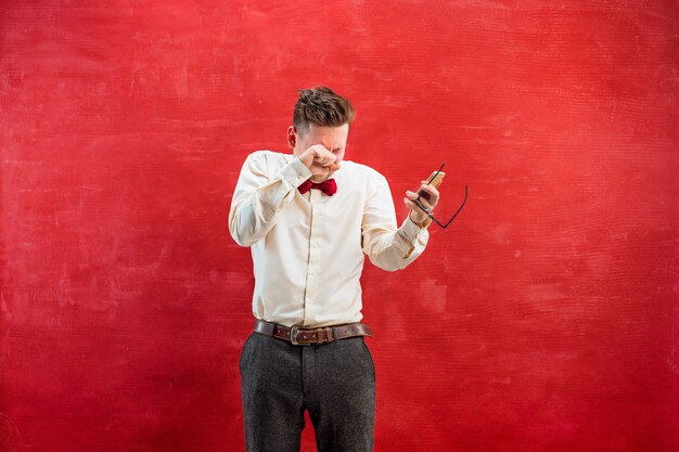 Portrait of puzzled man talking by phone on red