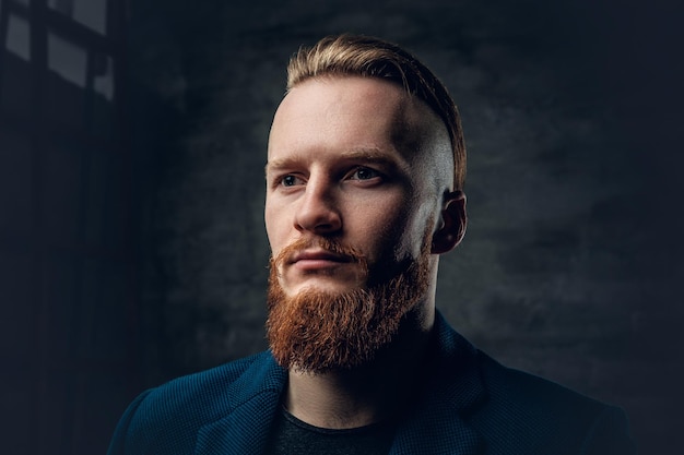 Free photo portrait of redhead bearded hipster male dressed in a blue jacket over grey background.