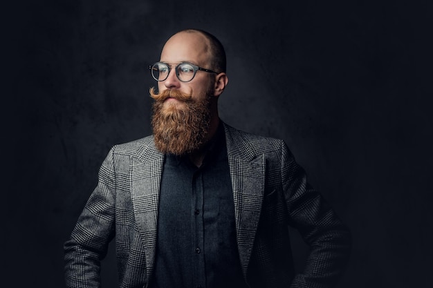 Free photo portrait of redhead bearded male in eyeglasses dressed in an elegant wool suit over grey background.