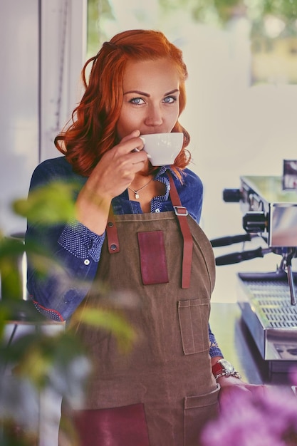 Ritratto di donna barista rossa in una piccola caffetteria.