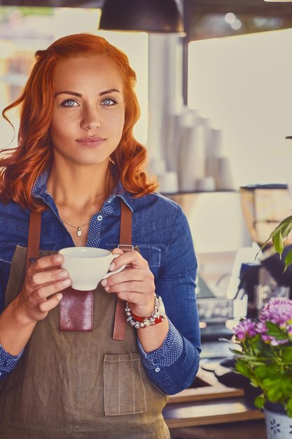 小さなコーヒーショップで赤毛の女性バリスタの肖像画。