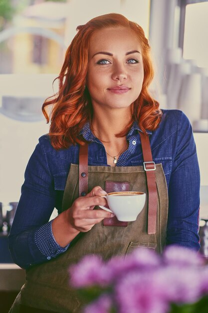 Portrait of redhead female barista in a small coffee shop.