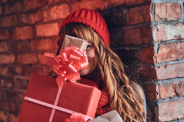 Portrait of redhead female in a warm clothes holds Christmas gift.