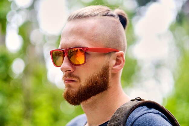 Portrait of redhead male in sunglasses over wild city park.