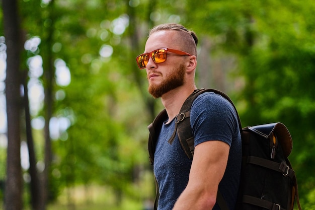 Portrait of redhead male in sunglasses over wild city park.