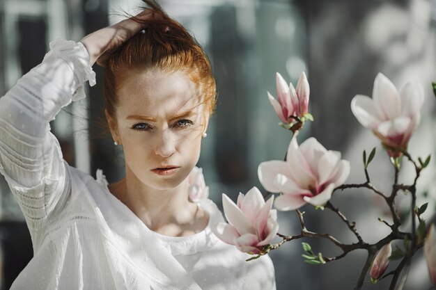 Portrait of redhead woman near a magnolia twig