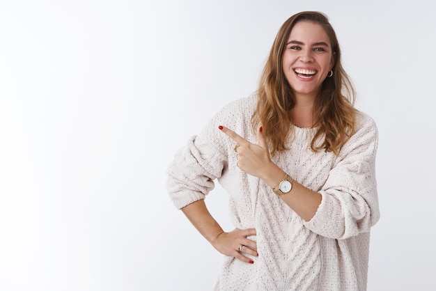 Портрет расслабленной радостной дружелюбной женщины в коротком свободном свитере, громко смеющейся