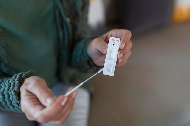 Portrait of relaxed mature woman taking a Selfswabbing home tests for COVID19 at home Senior woman using cotton swab while doing coronavirus PCR test at home Quarantine pandemic