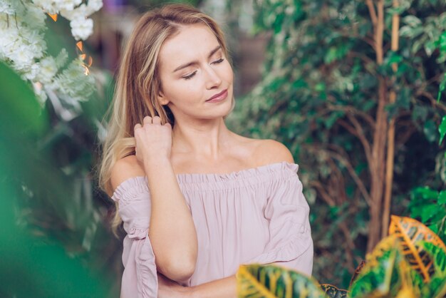 Portrait of relaxed young woman standing among the green plants