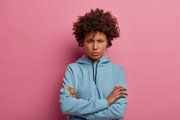 Portrait of resentful angry curly woman has unhappy grimace