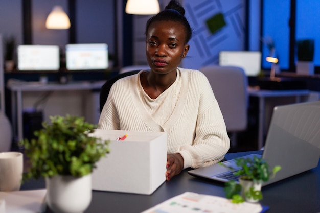 Portrait of resigned dismissed african american businesswoman packing objects